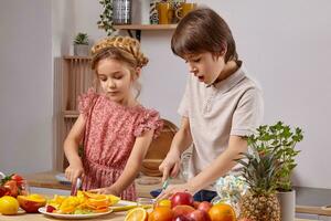 linda niños son Cocinando juntos en un cocina en contra un blanco pared con estantería en él. foto