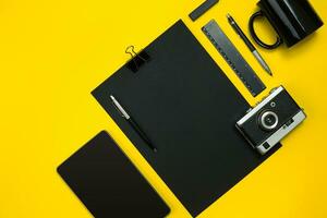 Black objects from the office on a yellow background. Work and creativity. Top view. photo