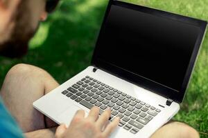 parte superior ver masculino manos utilizando cuaderno al aire libre en urbano ajuste mientras mecanografía en teclado, empresario persona de libre dedicación trabajando en computadora. foto