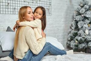 Beautiful young woman and her charming little daughter are hugging. photo