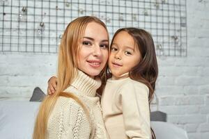 Beautiful young woman and her charming little daughter are hugging. photo