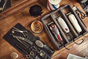 Hairdresser tools on wooden background. Top view on wooden table with scissors, comb, hairbrushes and hairclips, trimmer. photo