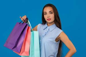 Photo of beautiful young woman with colorful shopping bags on the wonderful blue background
