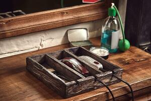 Hairdresser tools on wooden background. Top view on wooden table with scissors, comb, hairbrushes and hairclips, trimmer. photo