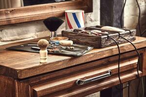 Hairdresser tools on wooden background. Top view on wooden table with scissors, comb, hairbrushes and hairclips, trimmer. photo