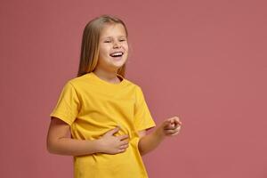 little girl in yellow t-shirt laughs pointing finger photo