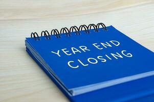 Year end closing text on blue notepad. Year end closing concept photo