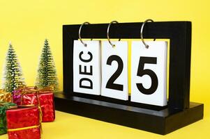 25 December calendar with Christmas tree and presents on yellow background. Christmas concept photo