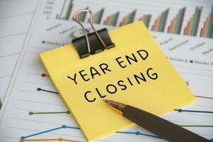 Year End Closing text on sticky note with statistic and graph background. Closing concept. photo