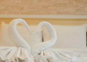 blanco en forma de cisne toallas en el cama a Bienvenido nuevo invitados en un lujo hotel a un playa recurso foto