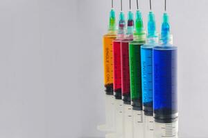 Syringes filled with colorful liquids are neatly arranged on an isolated background photo
