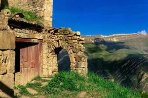 ruins of house in the abandoned village of Gamsutl overlooking the mountains photo