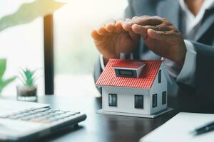 Female hands saving small house with a roof. insurance protective hand over house for protection and care, Concept of home and real estate Property insurance. close up of hands sheltering modern house photo