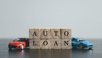 The word AUTO LOAN in the English language, written on wooden cubes. Finance and car loan, refinance, Investment and business concept with copy space. photo