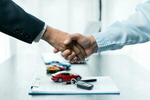Shaking hands, Car insurance agent consulting with policy. After agreeing to a contract for rent or sale of a car at workshop, loan car, insurance, sale, buying car and finance concept. photo