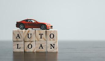 The word AUTO LOAN in the English language, written on wooden cubes. Finance and car loan, refinance, Investment and business concept with copy space. photo