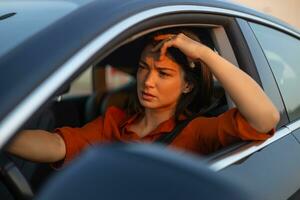 Nervous female driver sits at wheel, has worried expression as afraid to drive car by herself for first time. Frightened woman has car accident on road. People, driving, problems with transport photo