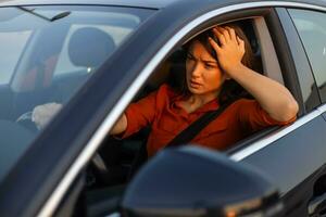 Nervous female driver sits at wheel, has worried expression as afraid to drive car by herself for first time. Frightened woman has car accident on road. People, driving, problems with transport photo