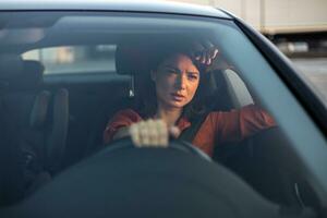 Sad businesswoman having problems while driving a car at sunset. Tired woman driving car photo