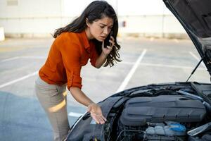 Woman opening car hood and look for trouble car breaks down and wating for insurance or someone to help after the car breaks down, park on the side of the road. Transportation accident concept. photo