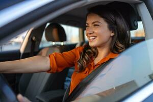 hermosa joven mujer conducción su nuevo coche a puesta de sol. mujer en coche. cerca arriba retrato de agradable mirando hembra con alegre positivo expresión, mujer en casual vestir conducción un coche foto