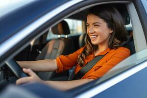 contento mujer conducción un coche y sonriente. linda joven éxito contento morena mujer es conducción un coche. retrato de contento hembra conductor direccion coche con la seguridad cinturón foto