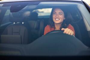 contento negocio mujer de viaje con su coche alrededor el ciudad. hermosa joven contento sonriente mujer conducción su nuevo coche a puesta de sol. foto