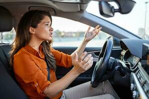 Stressed woman driver sitting inside her car. Angry female driver driving a car. Angry young woman stuck in a traffic jam. Woman annoyed in car. Girl stuck in traffic. photo