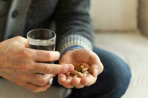 Hands with pills. Senior man hands holding medical pill and glass of water. Mature old senior grandfather taking medication cure pills vitamin. Age prescription medicine healthcare therapy concept. photo