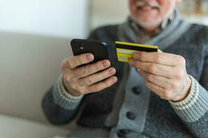 mayor hombre compras en línea participación teléfono inteligente pago con crédito tarjeta antiguo abuelo comprando en Internet entrar crédito tarjeta detalles. en línea compras entrega servicio. más viejo Generacion moderno tecnología uso foto
