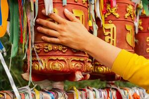 Person pilgrim female hand touching turning spinning Buddhist prayer wheel at Buddhist monastery. Prayer wheels in Buddhist stupa temple. Buddhism religion concept. photo