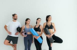 A group of female and male athletes stood and chatted amicably in the studio before beginning with the yoga class. photo