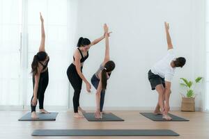 yoga instructor ayudando alumnos en haciendo yoga poses en el estudio, yoga clase concepto foto