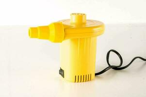 a yellow portable air pump on a white surface photo