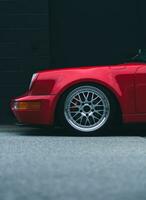 un rojo Porsche coche estacionado en frente de un negro pared foto