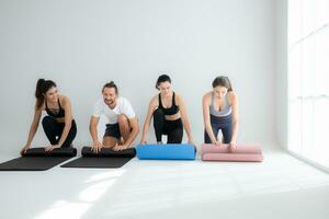 un grupo de hembra y masculino Atletas haciendo yoga ocupaciones a estudio, laminación arriba el yoga estera foto