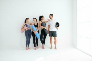 A group of female and male athletes stood and chatted amicably in the studio before beginning with the yoga class. photo