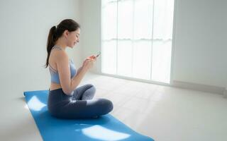 Young sporty women sitting rest on yoga mats and looking her smartphone. photo