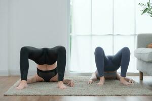 Young woman practicing yoga with instructor in house. Individual yoga class practicing in house photo