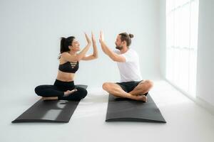 Young couple practicing yoga in a white room of studio. photo