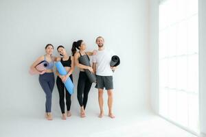 A group of female and male athletes stood and chatted amicably in the studio before beginning with the yoga class. photo