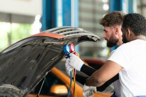 coche mecánico trabajando en un auto reparar comercio, inspeccionando el operación de el carros aire acondicionador y refrigerante. foto