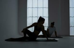 Silhouette of a young couple practicing yoga in the room. photo