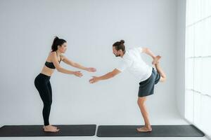 Young couple practicing yoga in a white room of studio. photo