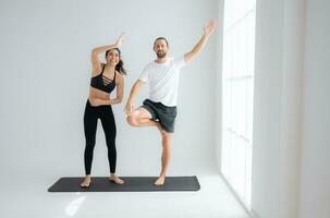 Young couple practicing yoga in a white room of studio. photo