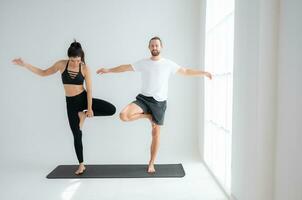 joven Pareja practicando yoga en un blanco habitación de estudio. foto