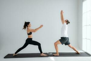 Young couple practicing yoga in a white room of studio. photo