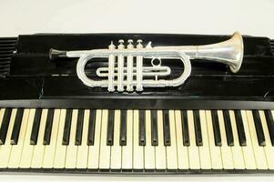 a silver trumpet on top of a piano keyboard photo