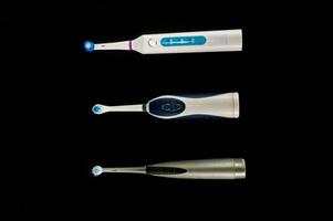 Tres diferente tipos de eléctrico cepillos de dientes son mostrado foto