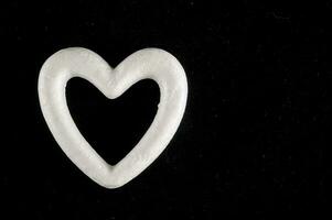 un blanco corazón conformado objeto en un negro antecedentes foto